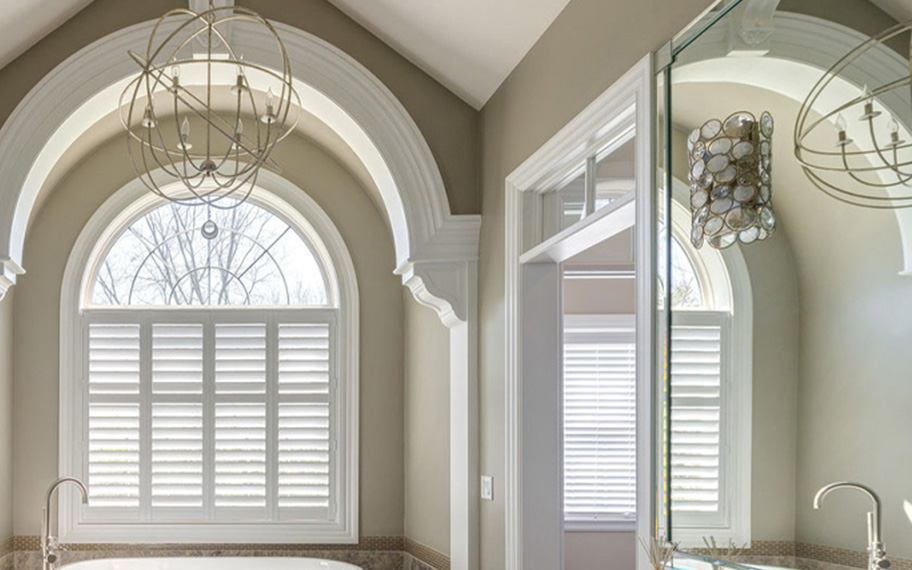 Polywood shutters insulate your windows and look beautiful too. White arched shutters in a fancy bathroom.