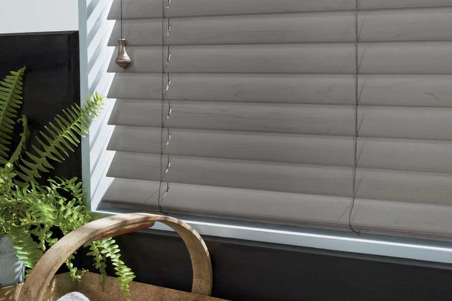 Close your faux wood bathroom blinds for privacy and darkness. A close-up view of gray blinds