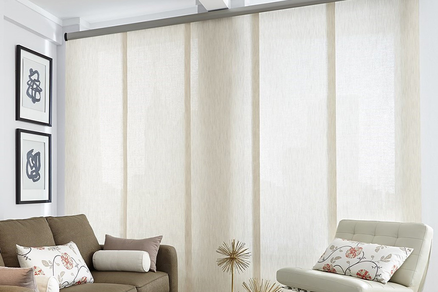 Find window treatments to complete any interior design among our extensive selection at Sunburst Shutters Orlando.  Long off-white window shades on a tall window in a modern living room