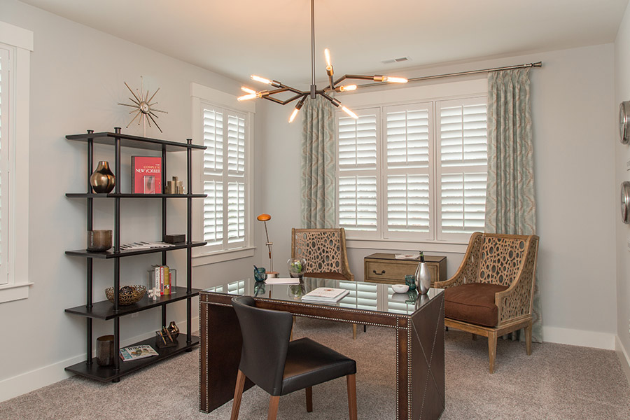 Colorful curtains can add a bit of flair with white Polywood shutters in Orlando. Sage green patterned curtains on white polywood shutters in an office.
