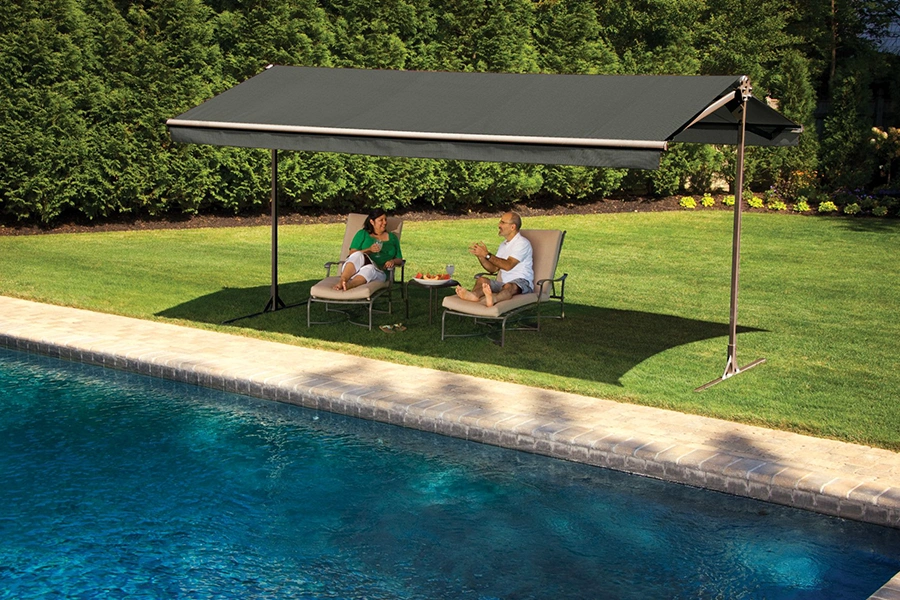A couple lounging under a freestanding awning next to a backyard pool