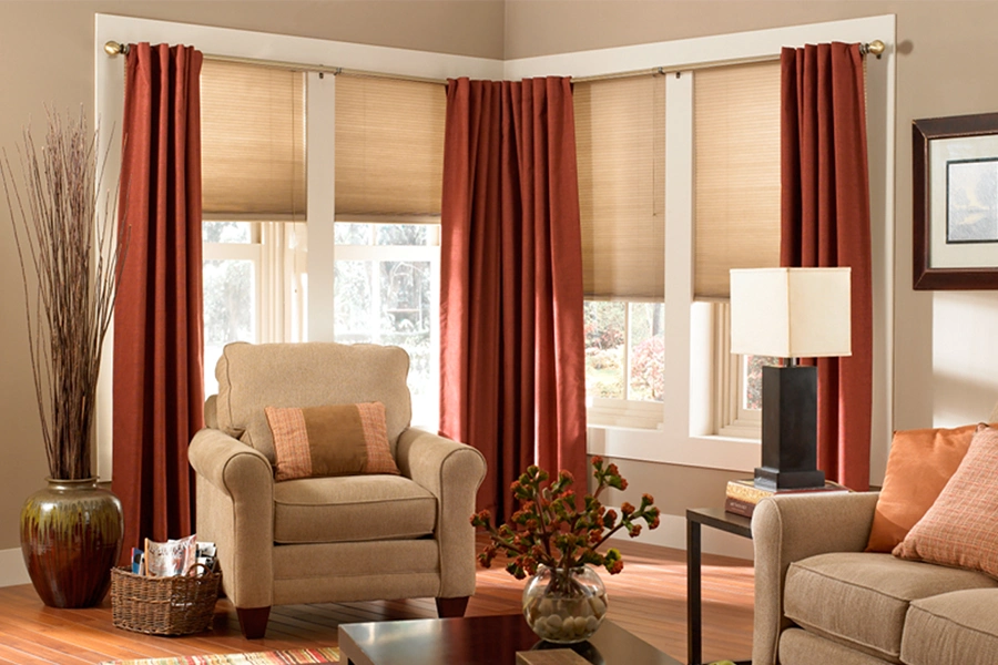 Cellular shades with layered drapes add allure and energy efficiency to this stylish space. Beige cellular shades layered with drapes in a stylish living space